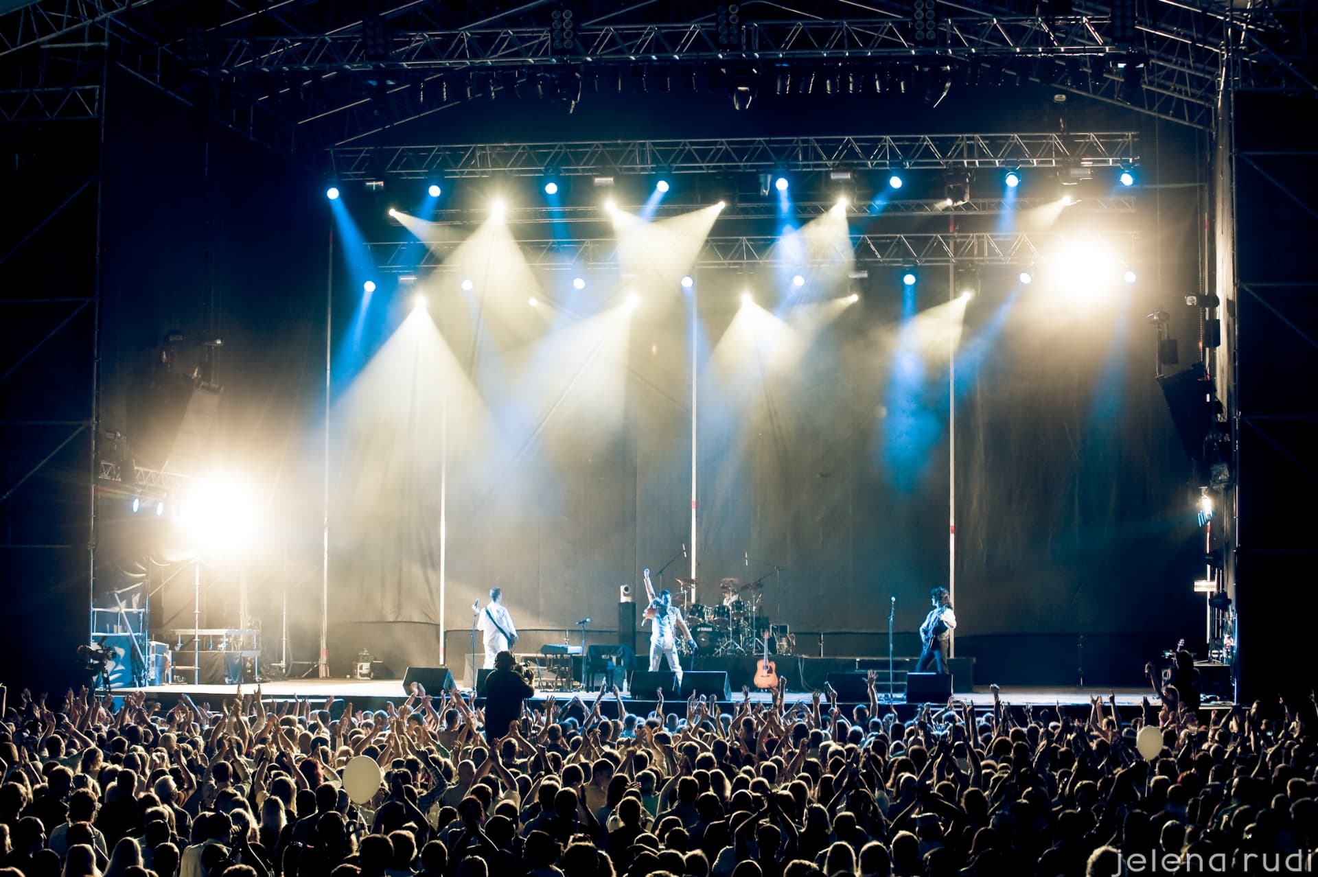Band op een groot festivalpodium met blauwe en witte spots
